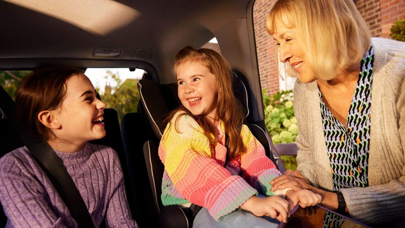 Image of woman puttung kids in their car.