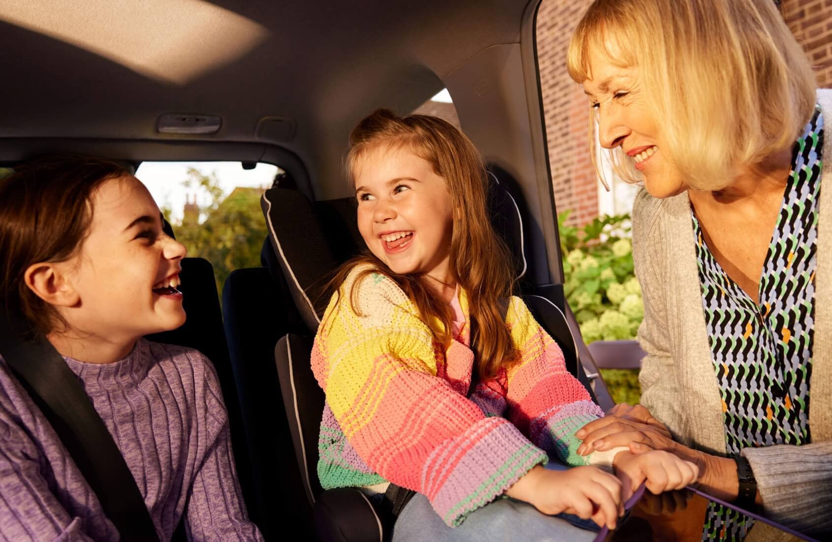 2 kids in a car with grandma seeing them off.