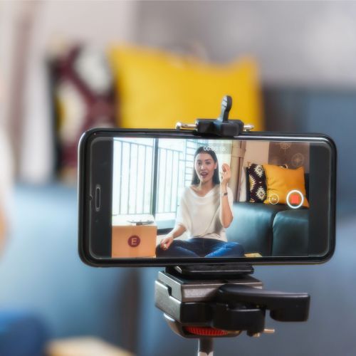 A young woman recording a video with tripod